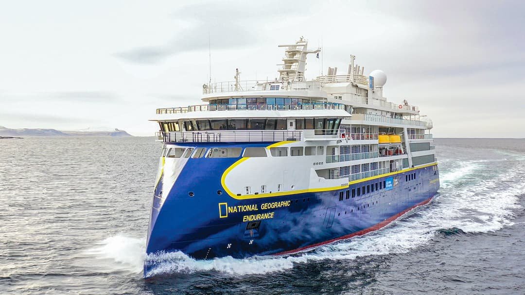 National Geographic Lindblad expedition ship with Zodiac boats exploring near towering glaciers